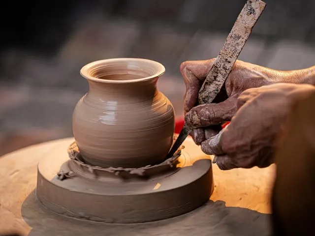 Artisan façonnant une poterie au tour, les mains dans l'argile.