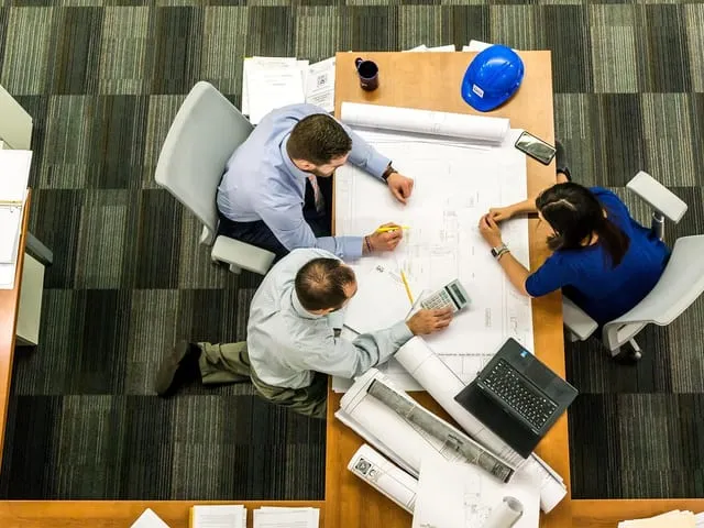 Petite équipe réunie autour d'une table de travail avec des documents.