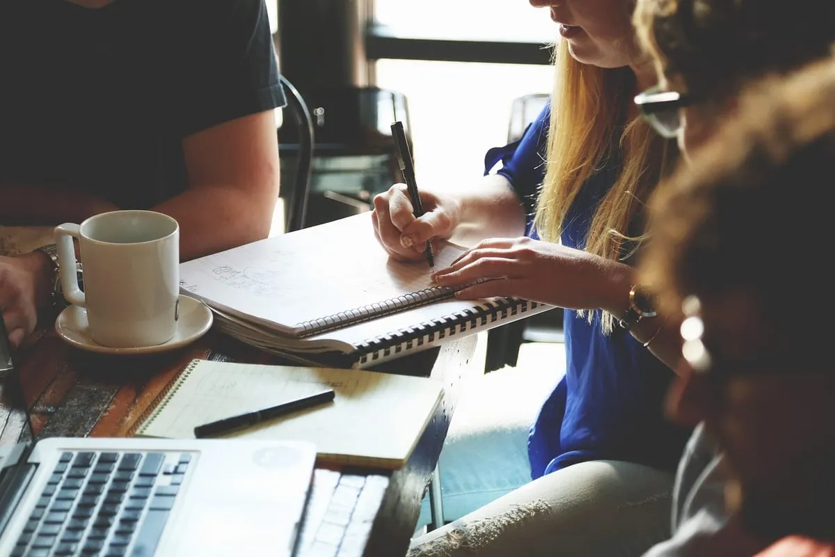Réunion de travail avec prise de notes et ordinateurs portables.