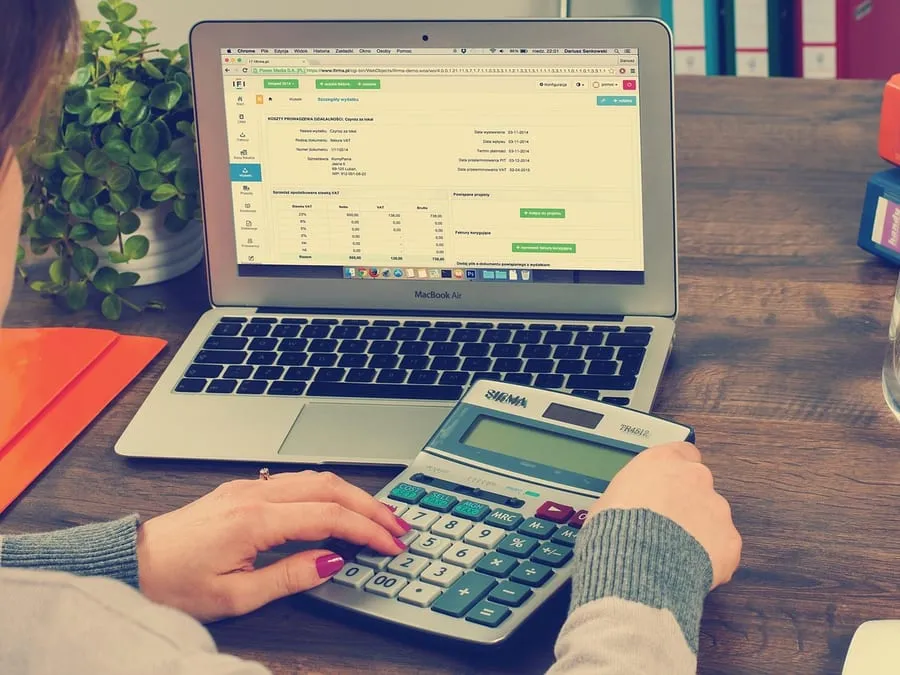 Comprendre le prix d'un projet web Mains utilisant une calculatrice à côté d’un ordinateur portable pour estimer un budget.