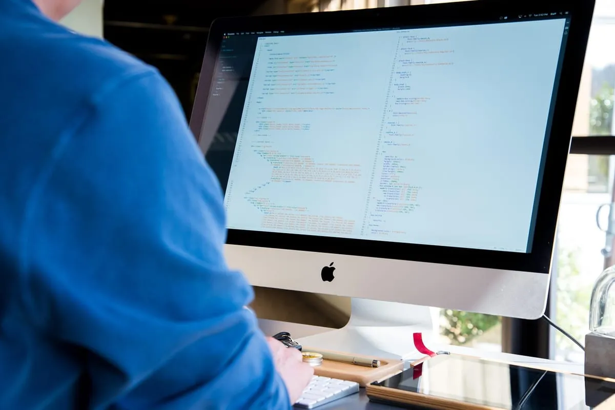 Développeur web au travail devant un grand écran affichant du code.