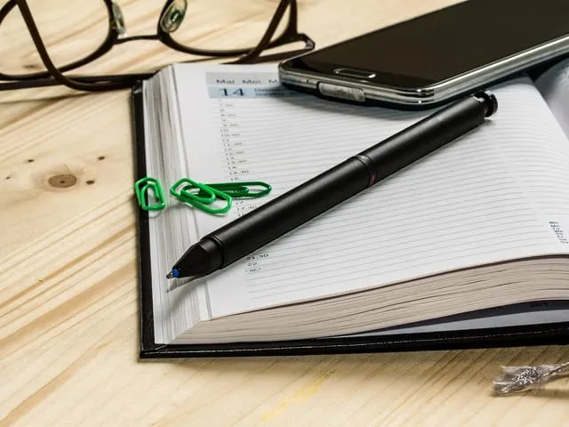 Agenda ouvert et smartphone posés sur un bureau, pour la prise de rendez-vous.
